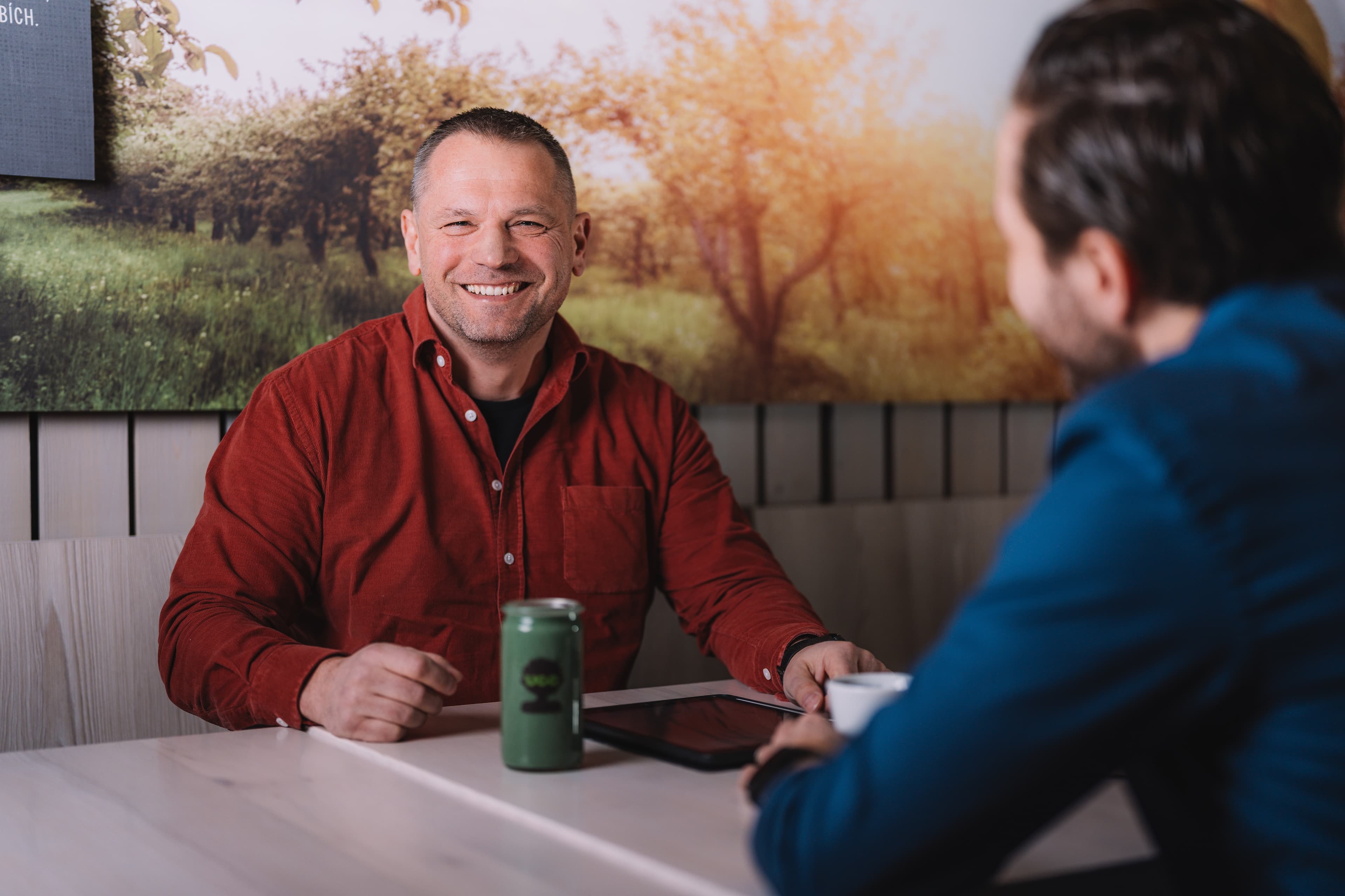 Dva smejici se muzi sedici u stolu s UGO napojem